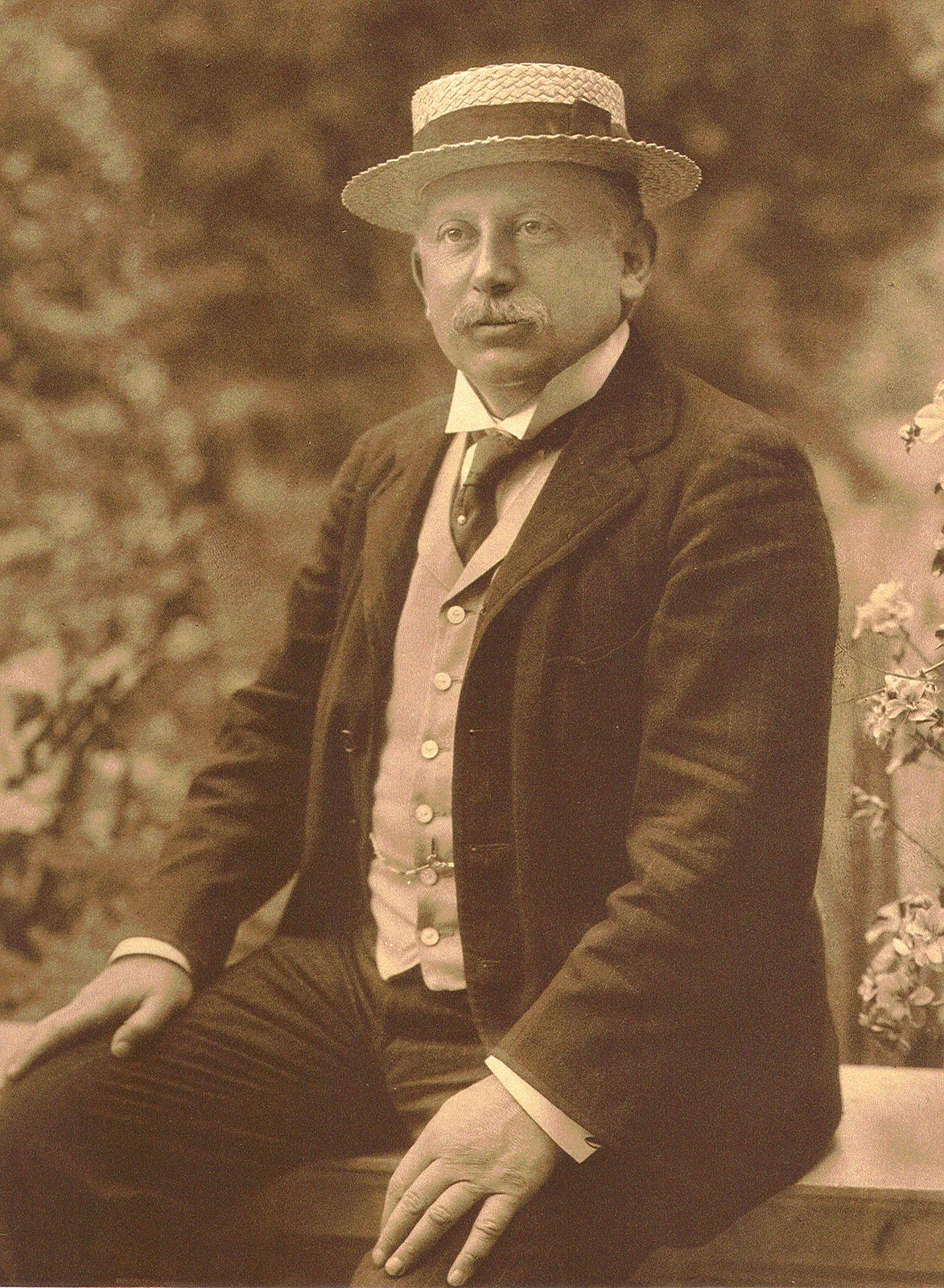 Alfred Beit seated outdoors in a straw boater and three-piece suit, in Dührkoop’s complete supplied 1905 portrait scan.
