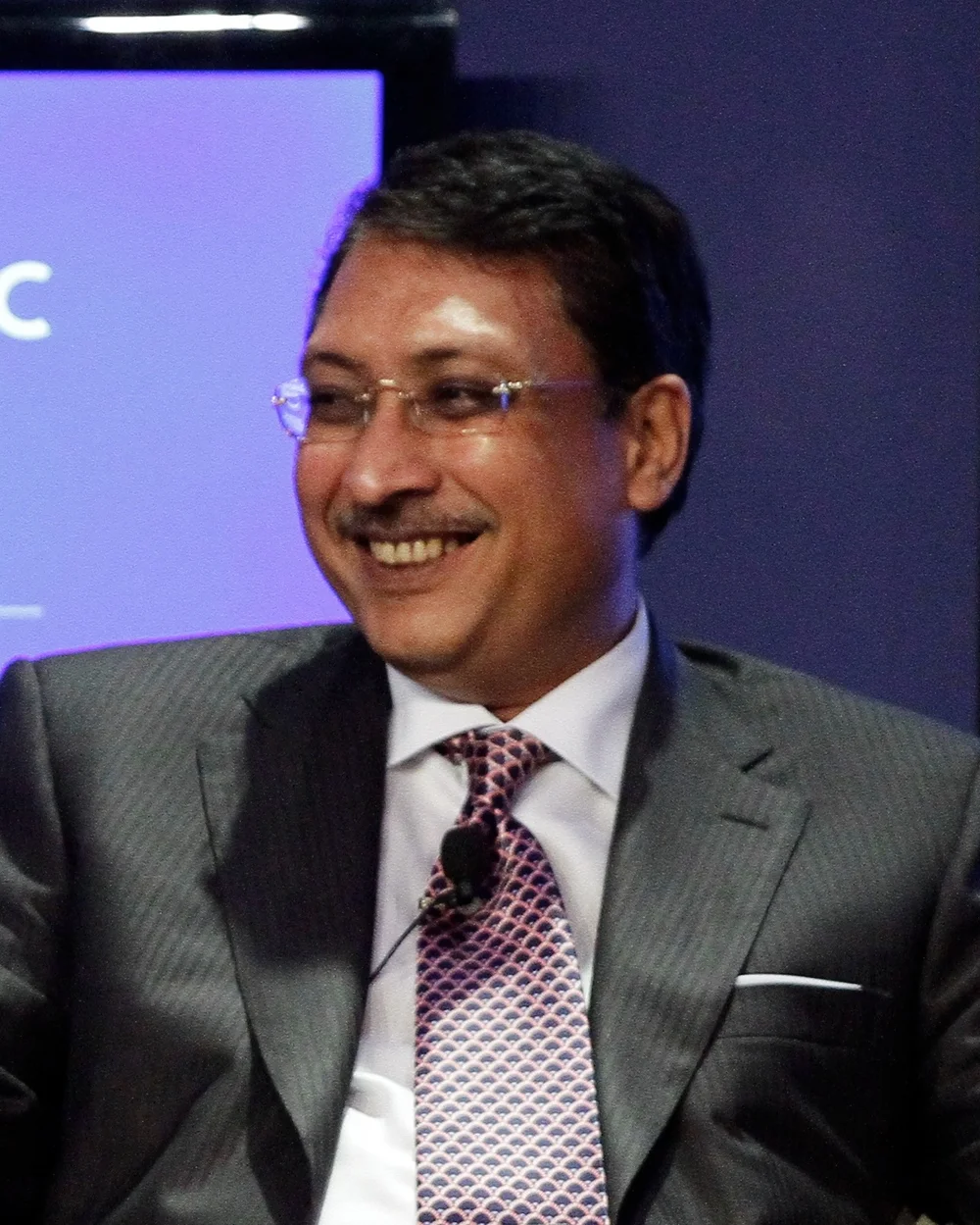 Aloke Lohia smiling in a suit and patterned tie during the 2012 World Economic Forum on East Asia in Bangkok.