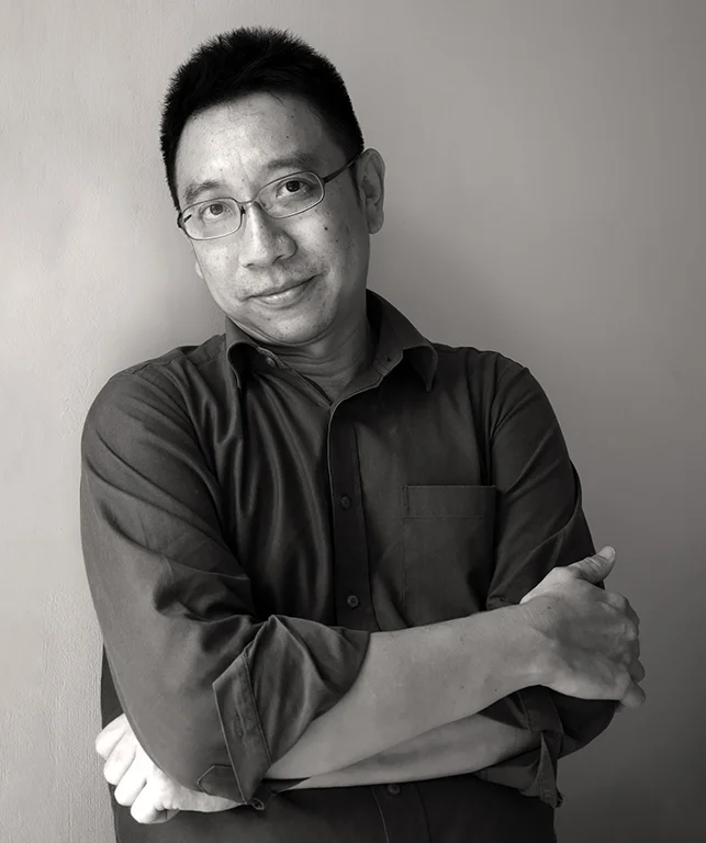 Alvin Pang wearing glasses and a dark shirt with his arms folded in a black-and-white 2018 portrait.