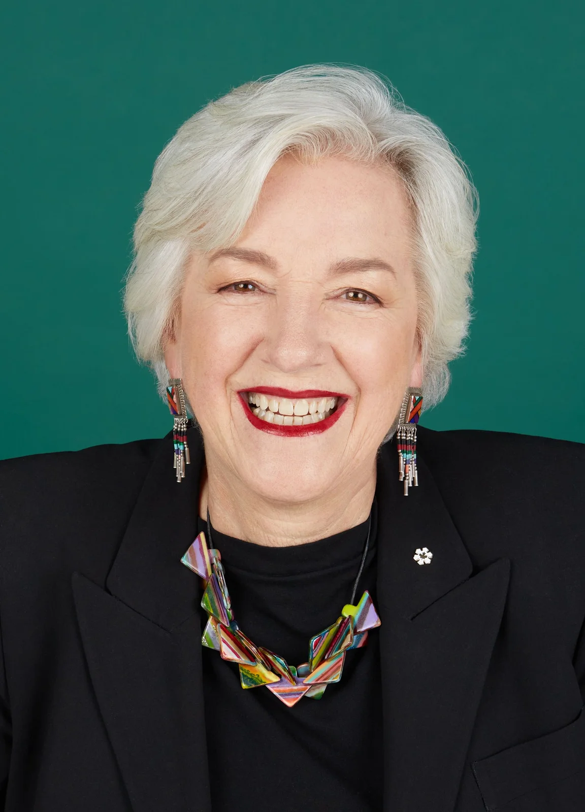 Annette Verschuren smiling against a green background in the complete December 2022 portrait.