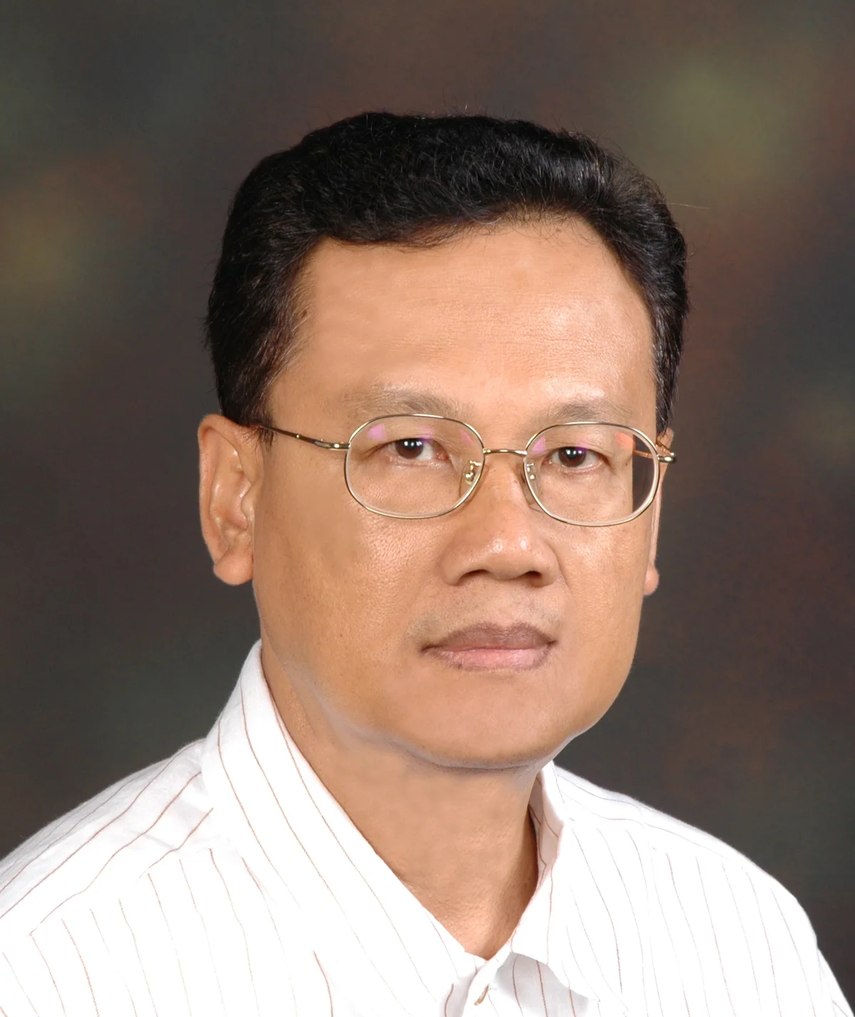 Portrait of Anwar Ridhwan wearing glasses and a light striped shirt.