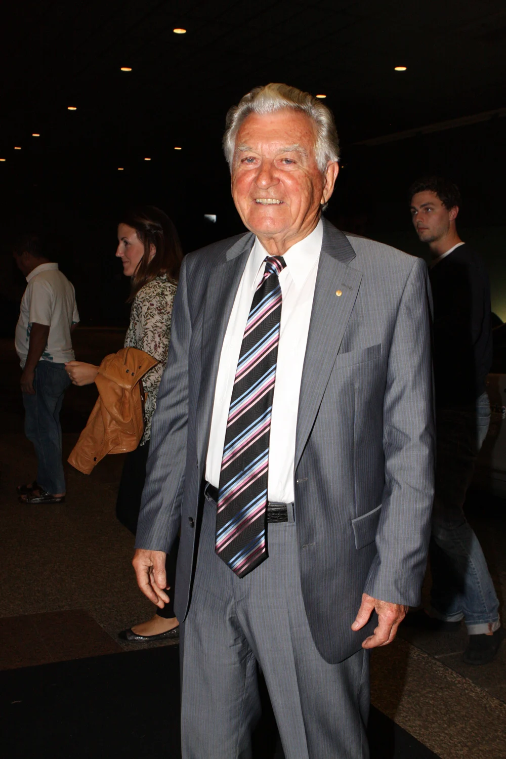 Bob Hawke smiling in a grey suit and striped tie, with other attendees behind him, in March 2012
