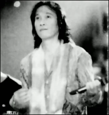 Black-and-white photograph of a young Chrisye playing a guitar.
