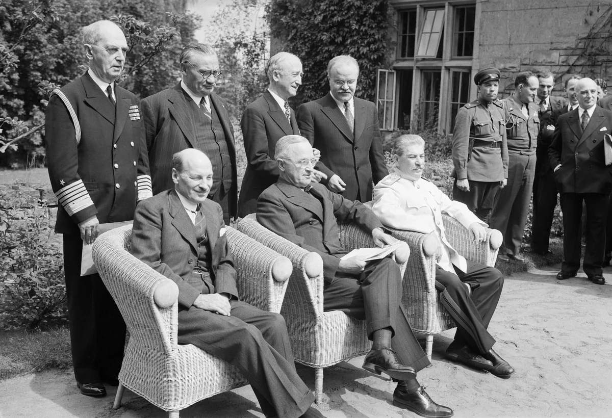 Clement Attlee seated at left beside Harry Truman and Joseph Stalin at Potsdam on 1 August 1945, with officials standing behind them.
