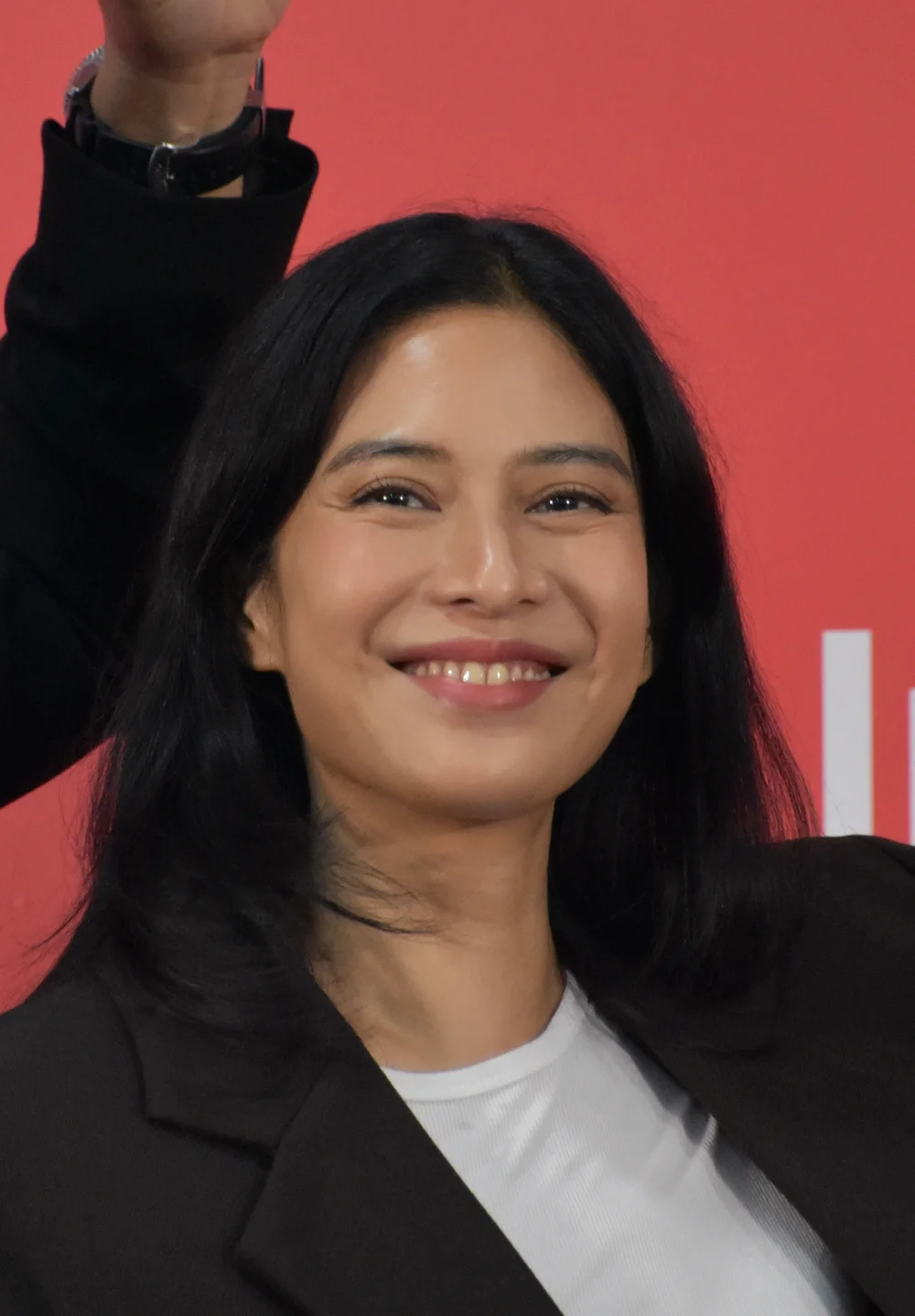 Dian Sastrowardoyo smiling and raising an arm at the 2026 Busan International Film Festival.