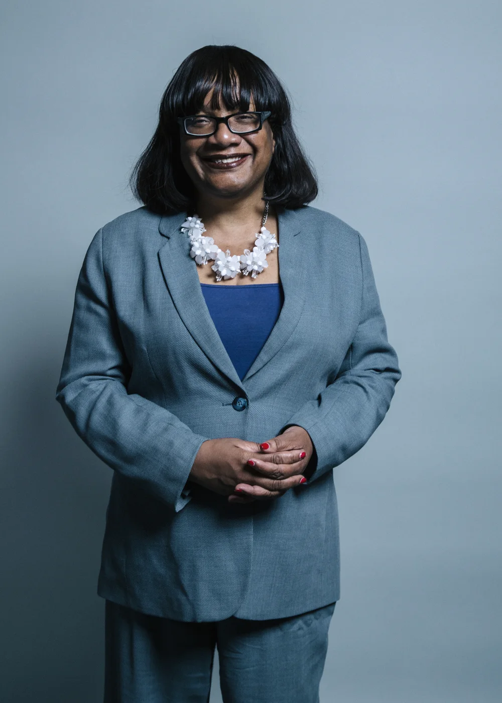 Complete 2017 Chris McAndrew official portrait of Diane Abbott standing in a grey jacket with hands clasped.