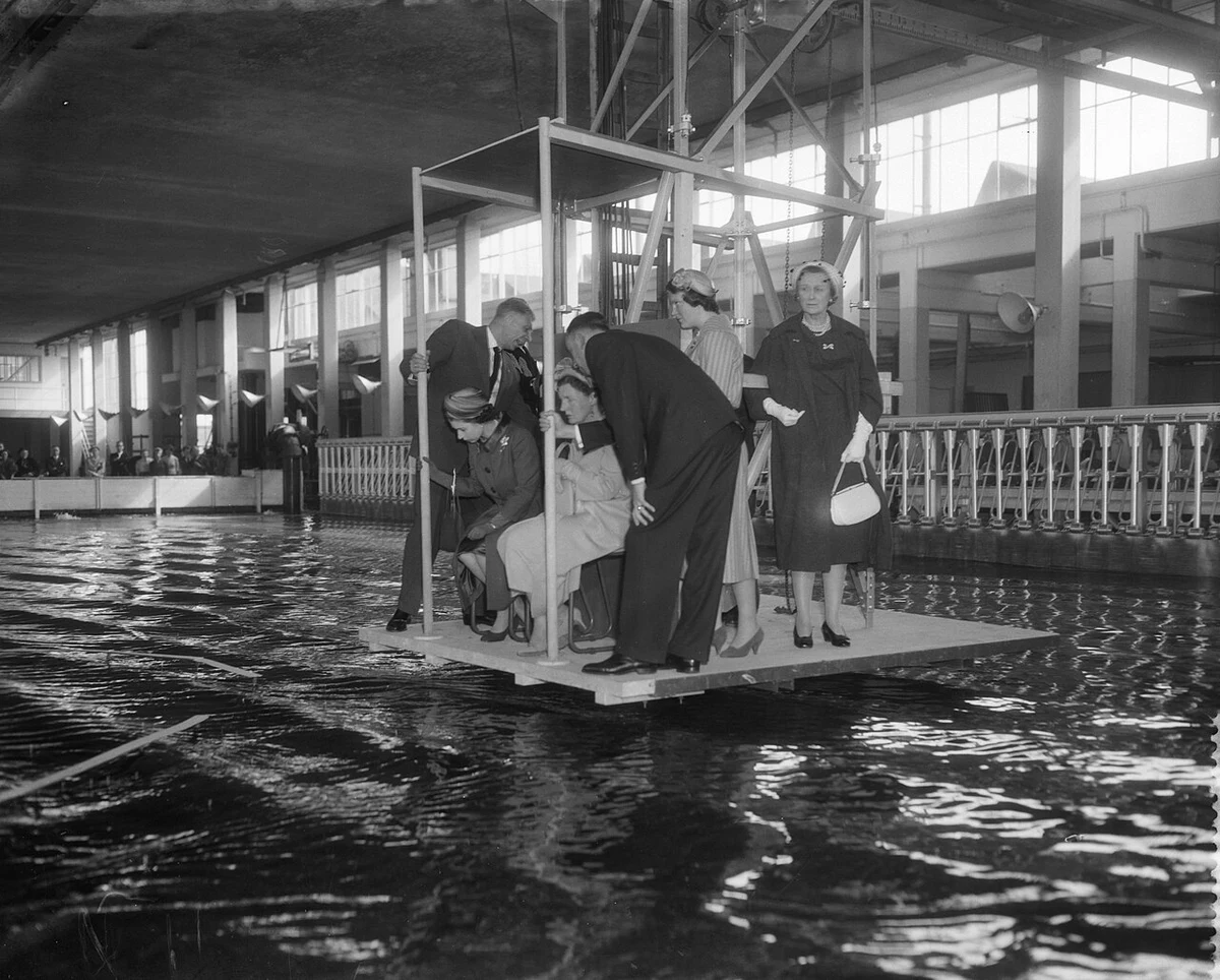 Elizabeth II seated at the left of a central group above a water basin during the 1958 Delft laboratory visit, with the complete group and building retained.