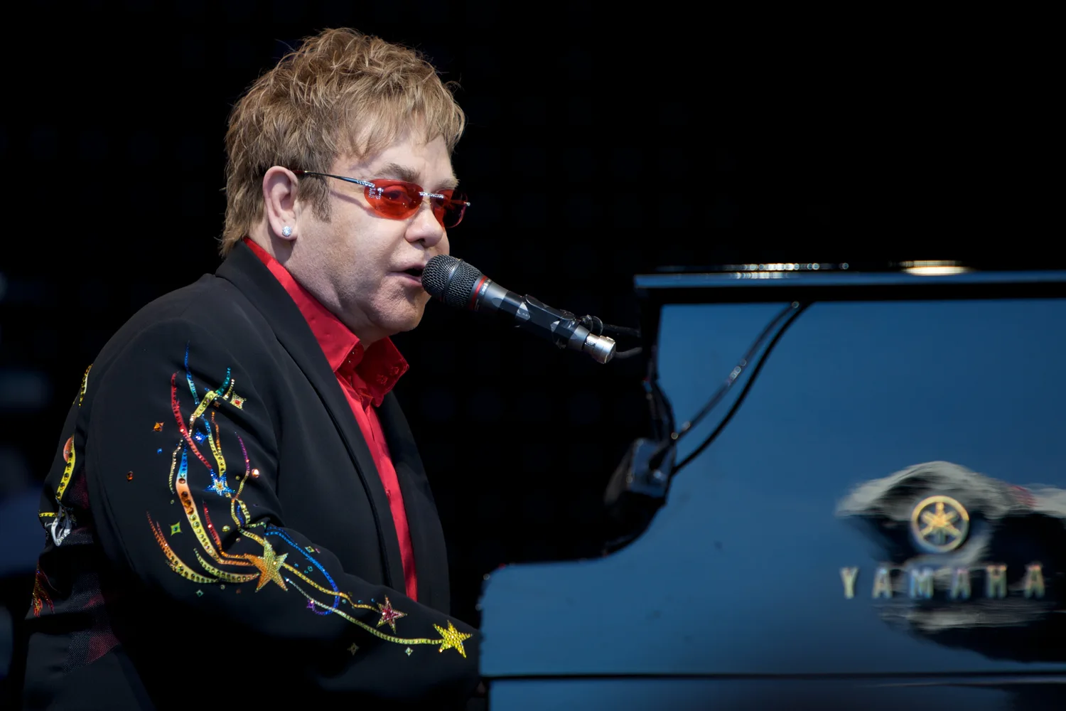 Elton John singing at his piano in Skien in 2009, wearing red glasses ...