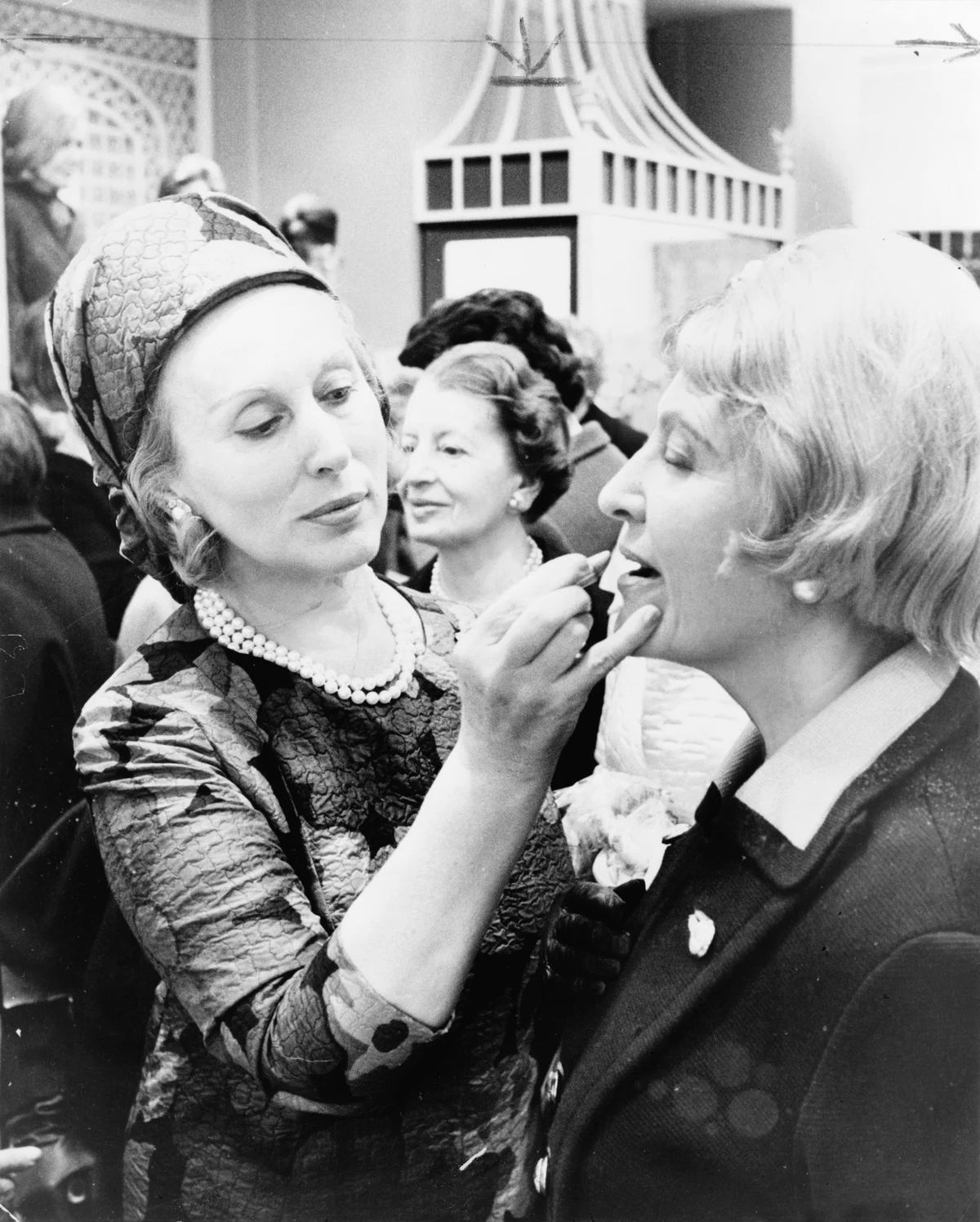 Estée Lauder at left applying lipstick to a customer at right in 1966, with the complete original scan and its publication marks retained