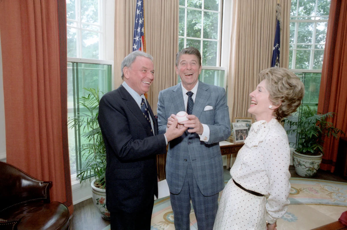 Frank Sinatra at left presenting a baseball to President Ronald Reagan, with Nancy Reagan at right, in the Oval Office in June 1981