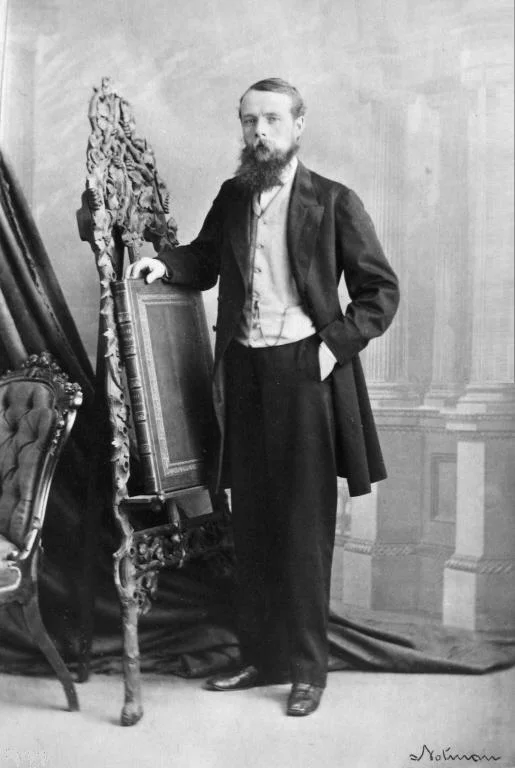 George Stephen stands beside an ornate chair in William Notman’s complete 1865 Montréal studio photograph, with the studio signature visible below.