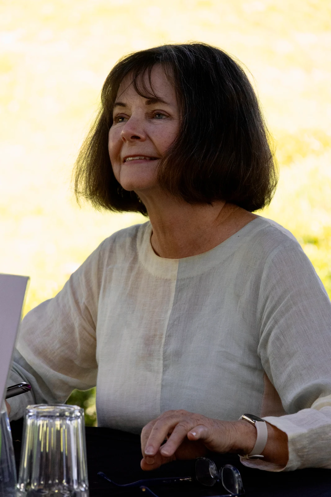 Geraldine Brooks seated at Adelaide Writers’ Week in March 2025, wearing a light blouse, with her hands, glass and table retained.