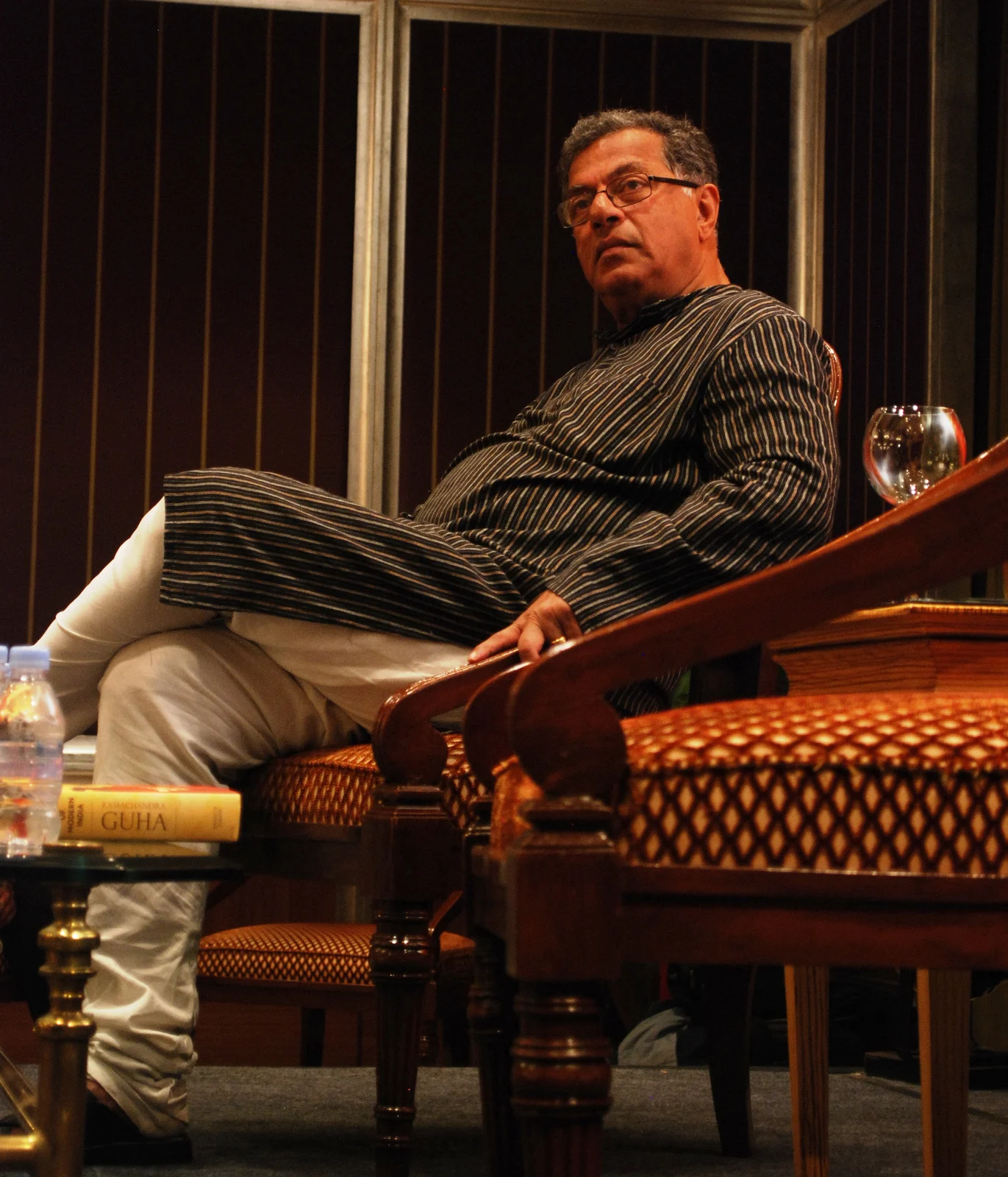 Pushkar V’s complete 2010 photograph of Girish Karnad seated in a chair, with table, book, bottles and glass retained in the frame