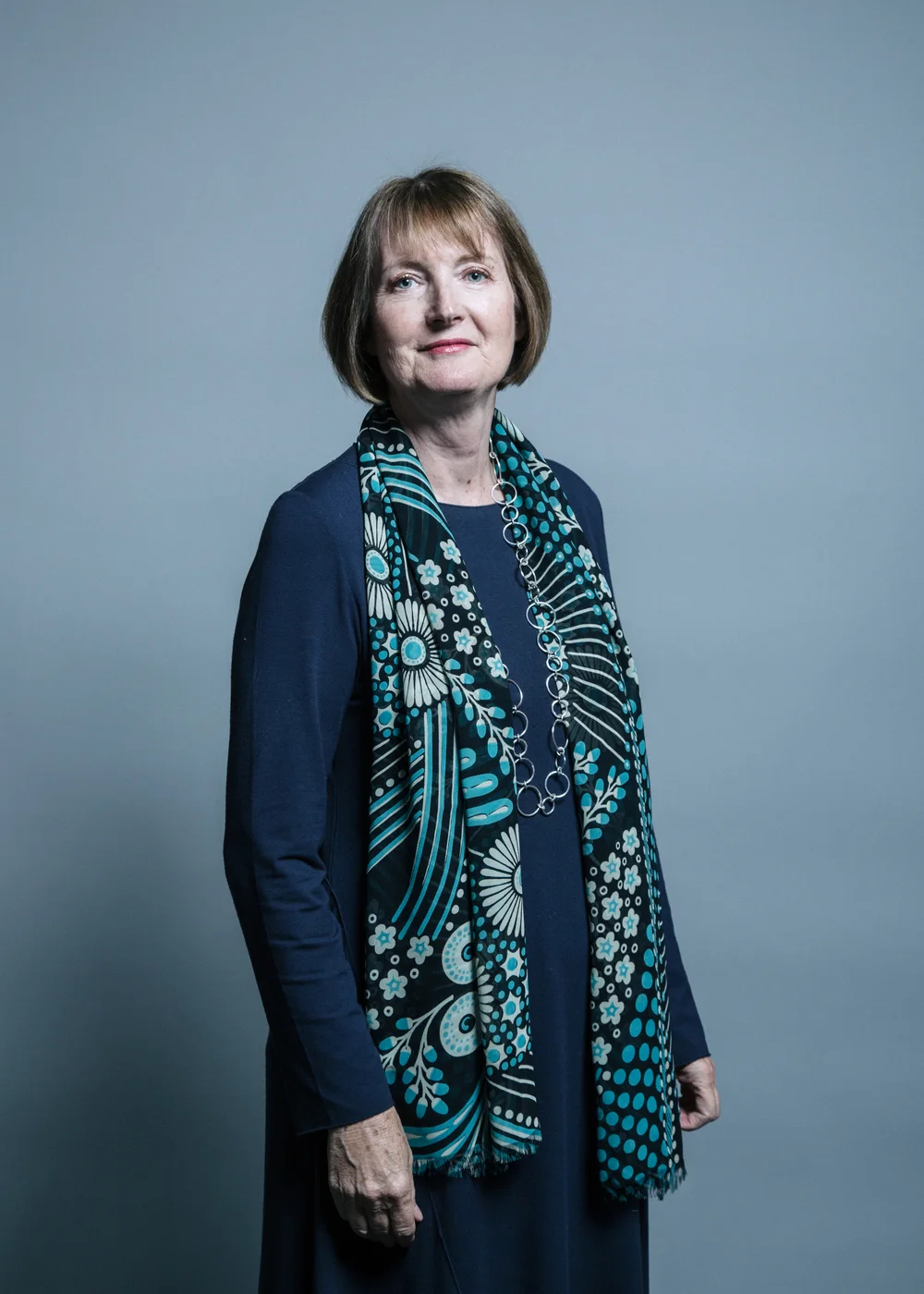 Complete 2017 Chris McAndrew portrait of Harriet Harman standing with a patterned scarf, hands and surrounding headroom retained.