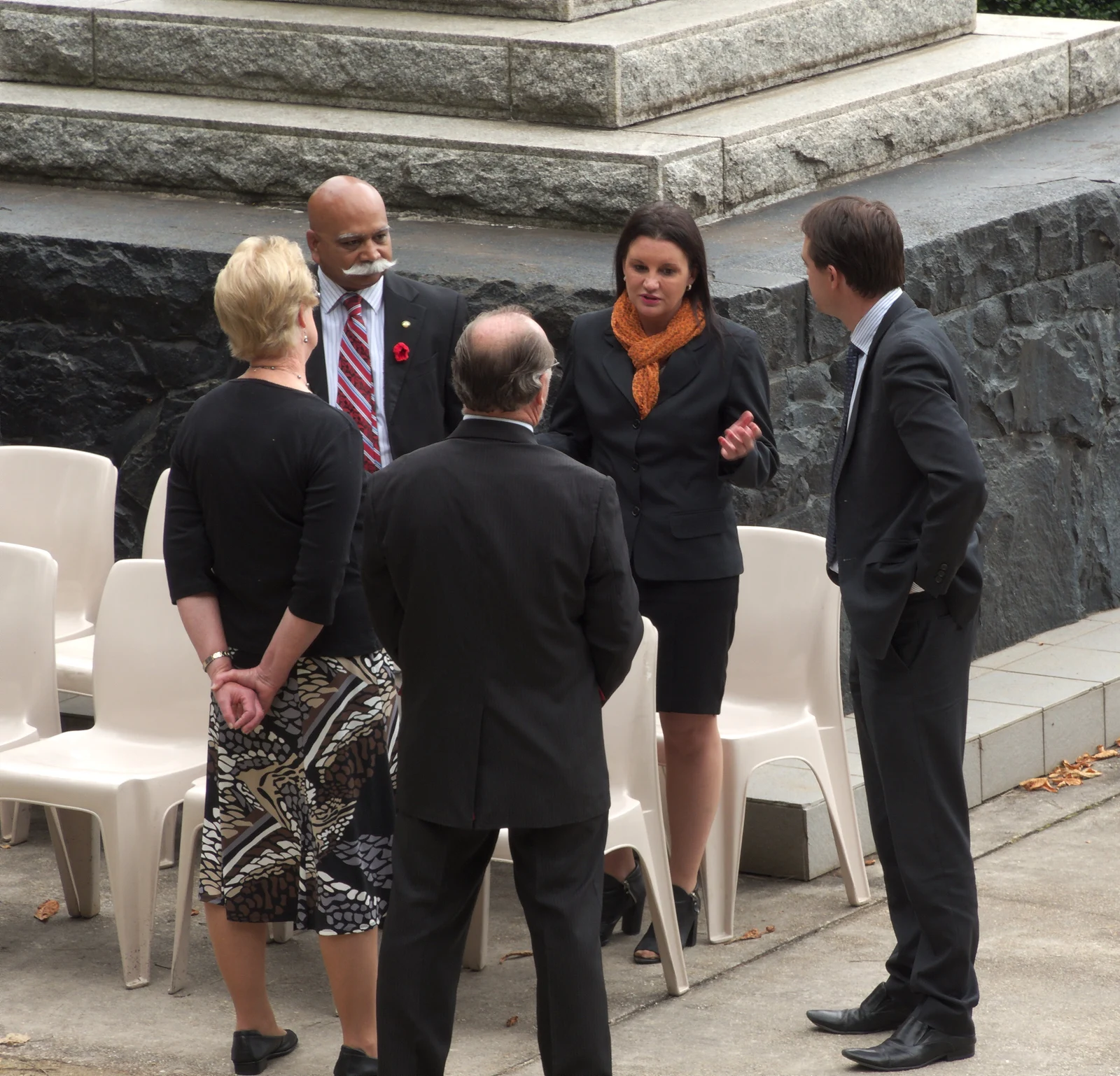 Jacqui Lambie, second from right wearing an orange scarf, talks with other attendees at a Burnie memorial unveiling; the entire supplied group photograph is retained.