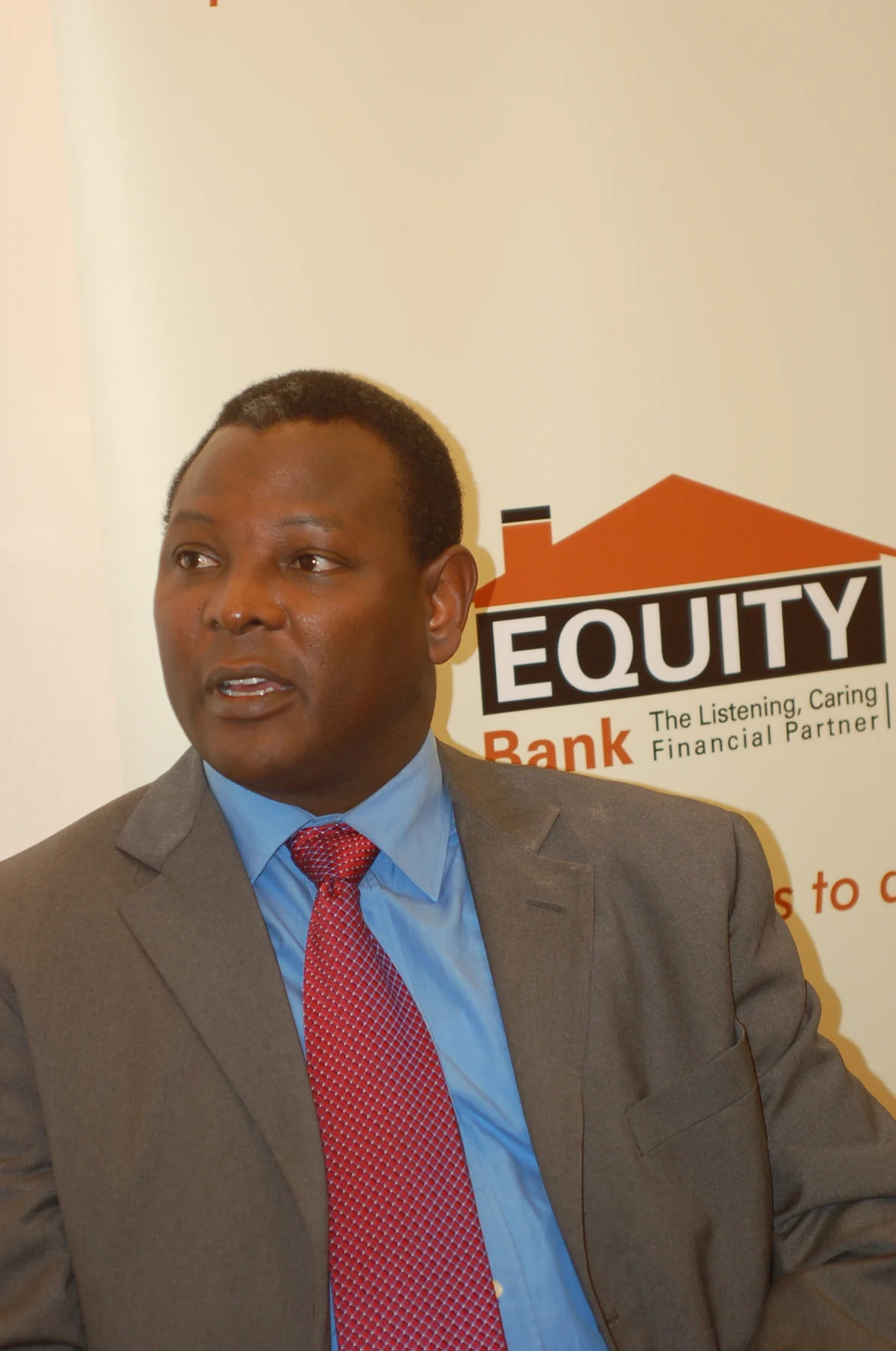 James Mwangi in a grey suit, blue shirt and red tie before an Equity Bank banner, photographed by Erik Hersman in March 2007.