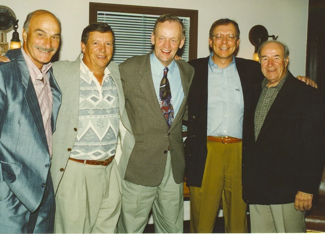 Jean Chrétien in the centre of a five-man group photograph dated 1996, smiling in a checked jacket and tie.