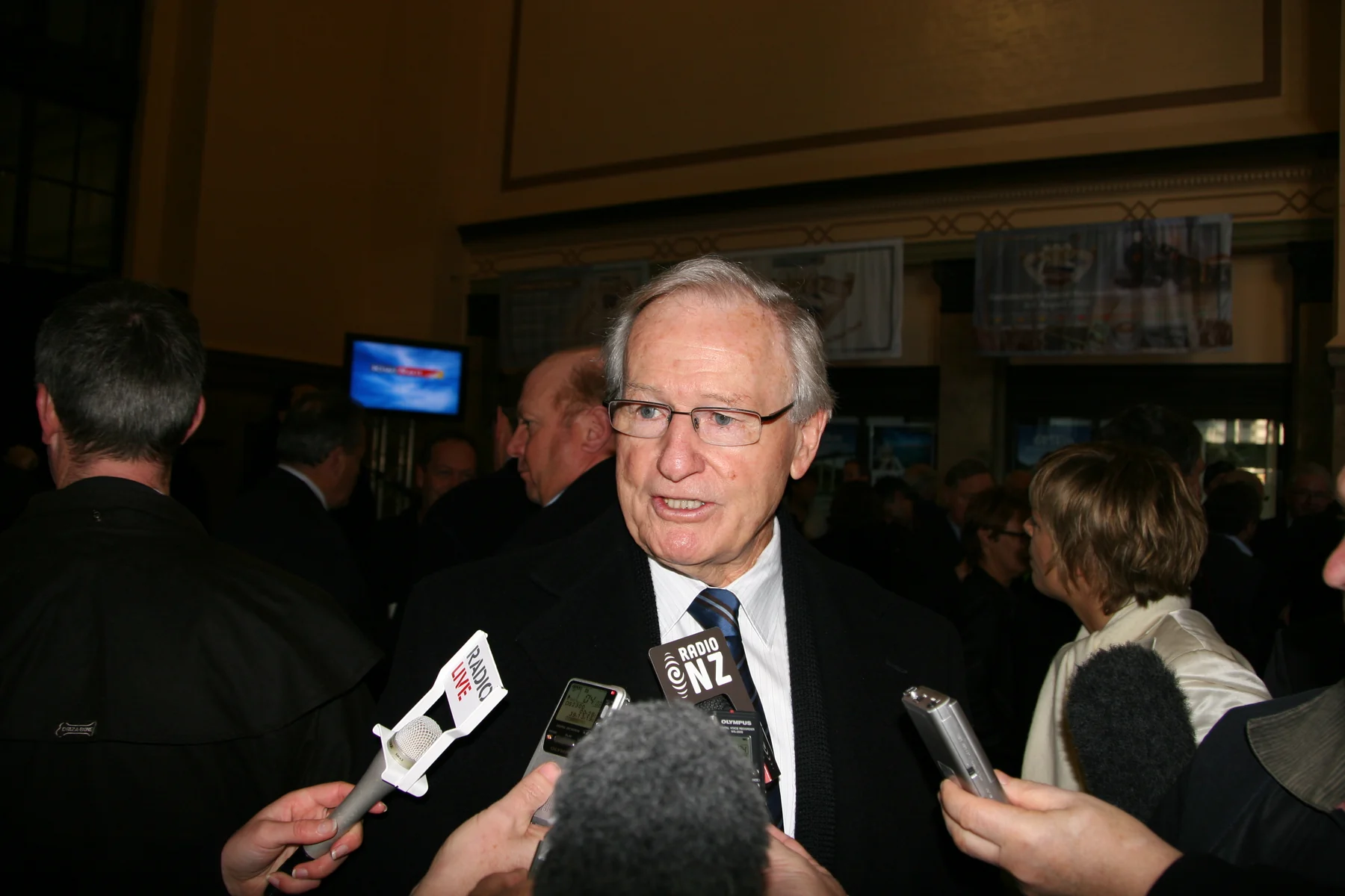 Jim Bolger answering reporters at a KiwiRail press conference in July 2008, with the complete photograph showing microphones and the surrounding room.