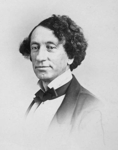 John A. Macdonald in a nineteenth-century William Notman studio portrait, shown from the chest upward in a dark coat and bow tie.