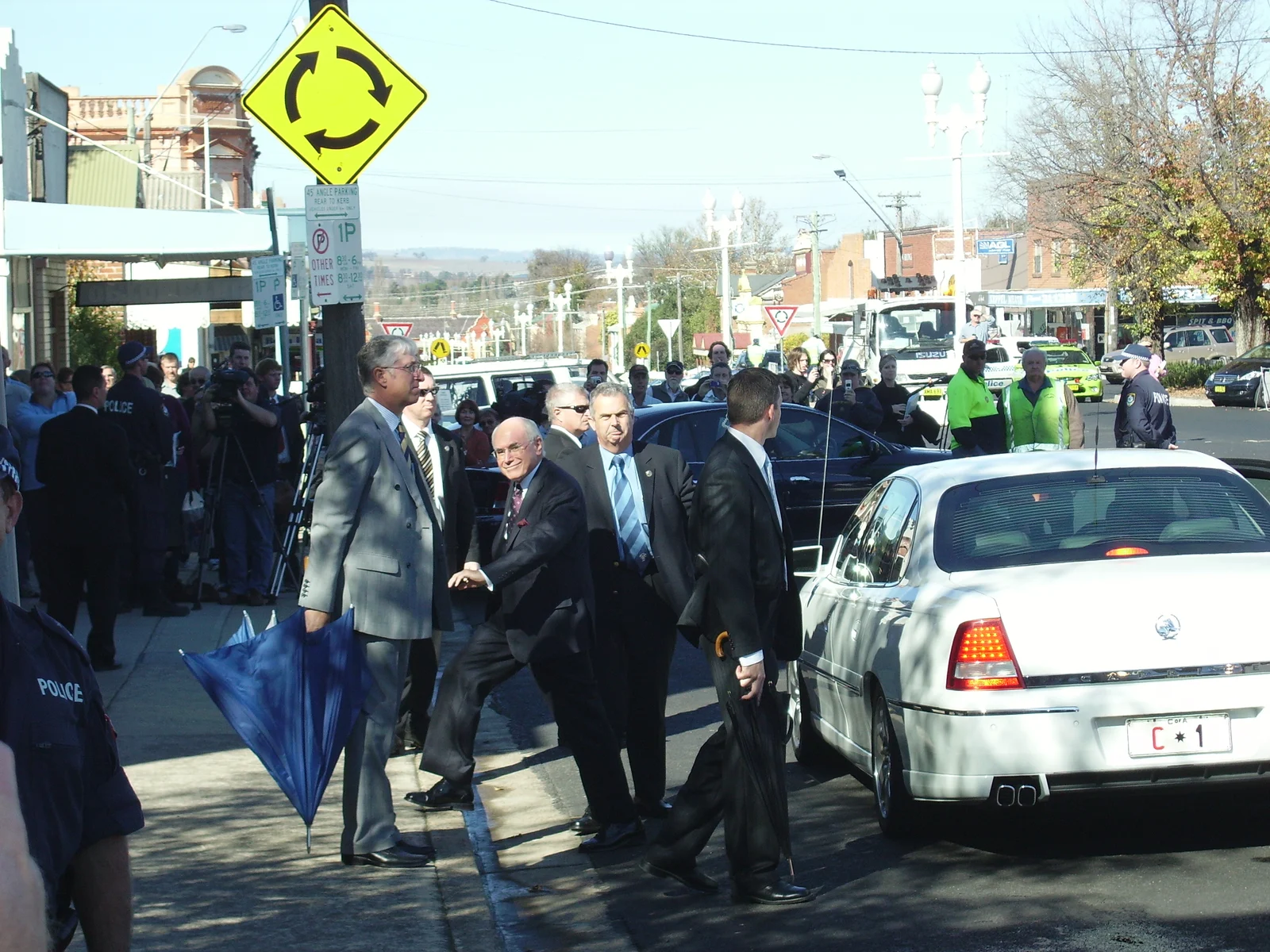 John Howard beside his white official car among security officers and onlookers on a Bathurst street in May 2007