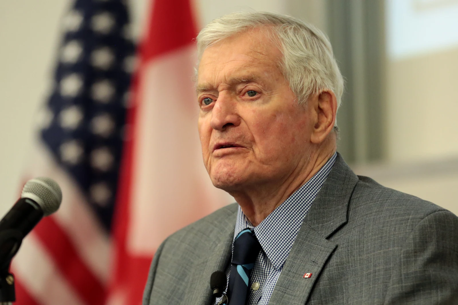 John Turner speaking beside a microphone with a United States flag behind him at Arizona State University in February 2018