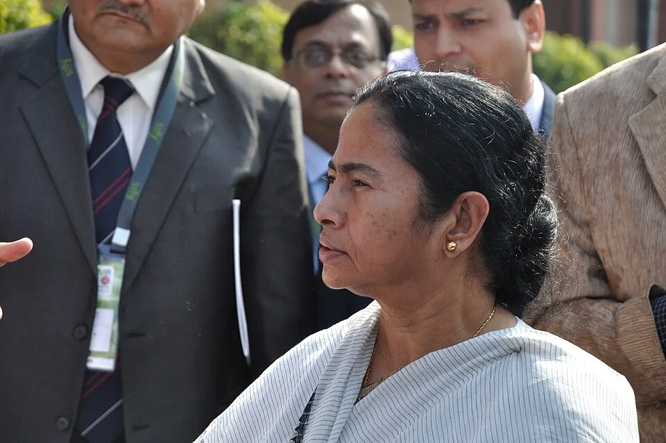 Mamata Banerjee appears in left-facing profile at the Infocom exhibition in Kolkata in December 2011, with several people standing behind her.