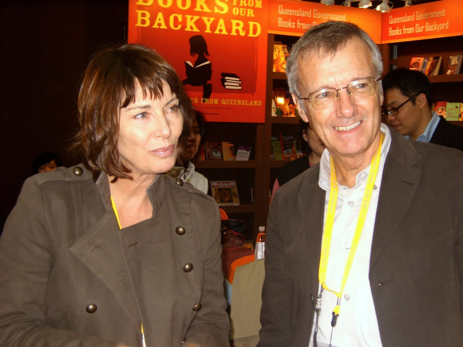 Full Rico Shen photograph at the 2008 Taipei book exhibition: Maureen Wheeler stands at left in a dark buttoned jacket beside Tony at right; booth and surrounding people remain uncropped.