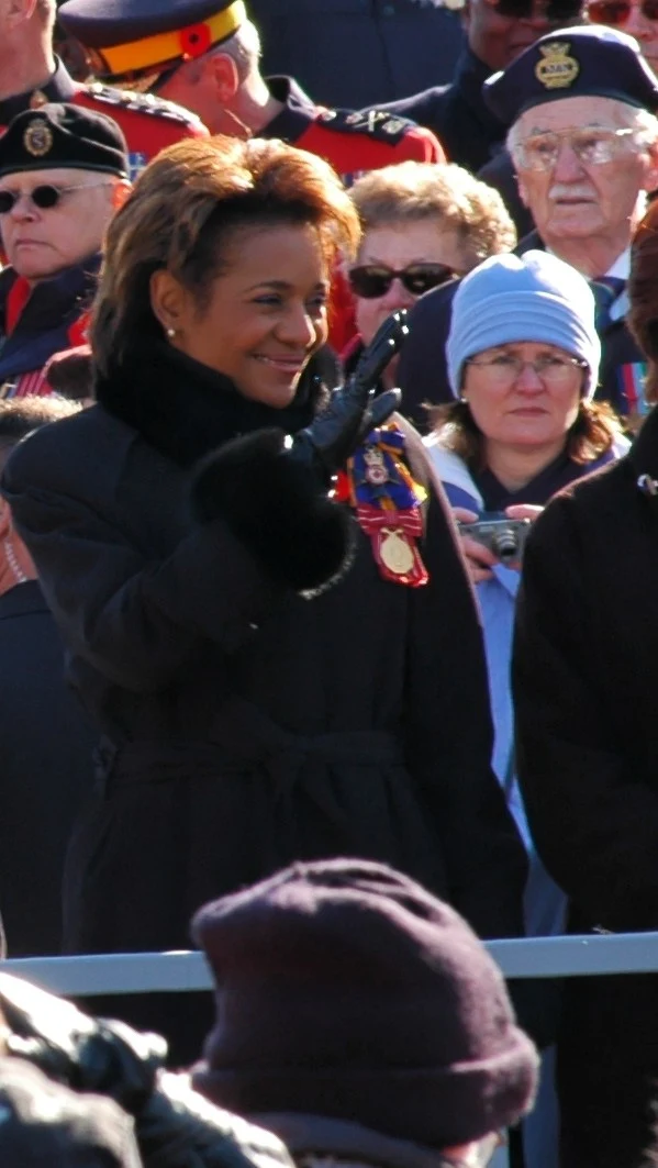 Michaëlle Jean in a dark coat with decorations at Remembrance Day in Ottawa on 11 November 2007, surrounded by veterans and attendees; all supplied background figures remain.