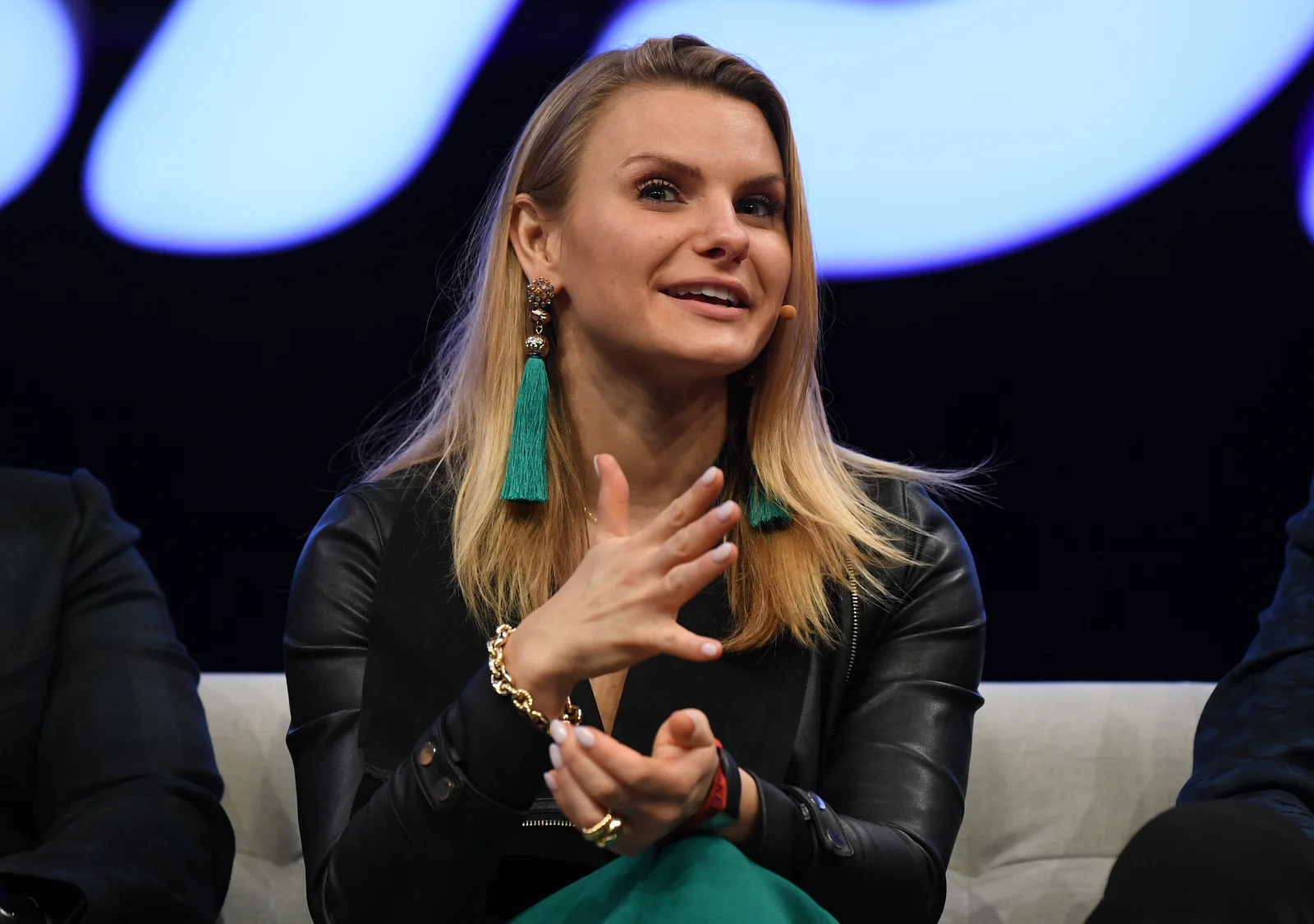 Michele Romanow seated with a microphone at Collision in Toronto in May 2019; the full event frame retains parts of neighbouring panelists.