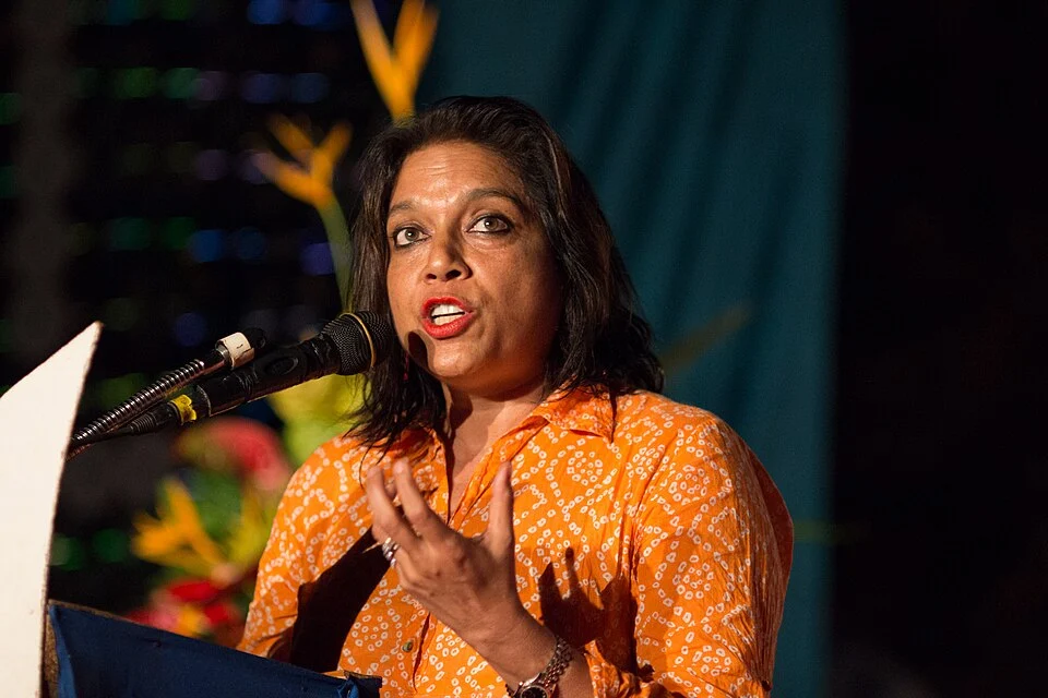 Mira Nair speaking into a microphone in an orange outfit at Zanzibar International Film Festival in 2013