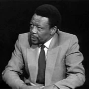 Mongane Wally Serote seated at a desk in Serge Aspeslag’s November 2006 black-and-white photograph.