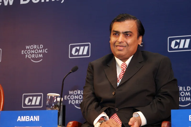 Mukesh Ambani seated at the India Economic Summit in New Delhi in December 2007, with the entire supplied forum frame, name card, glass and adjacent seating.