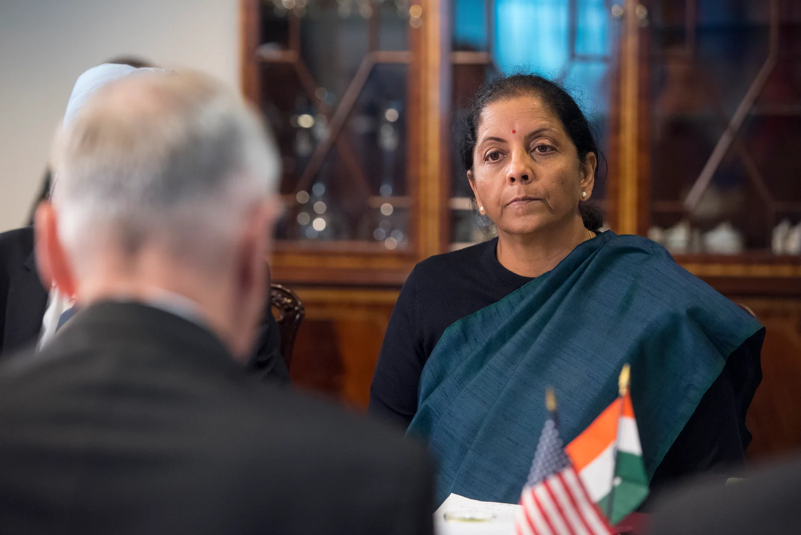 Nirmala Sitharaman sits at right during a Pentagon meeting in December 2018, with James Mattis in the left foreground and both countries’ flags visible.