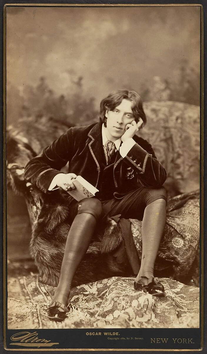 Complete 1882 Sarony cabinet photograph of Oscar Wilde seated with his cheek on his hand, retaining the card’s printed name, studio signature and copyright imprint