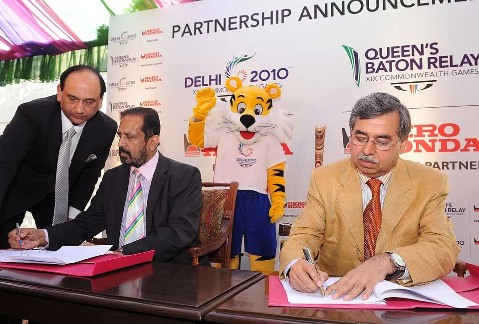 Pawan Munjal at right signs a Commonwealth Games partnership agreement in New Delhi in December 2009; the complete ceremony frame is retained.