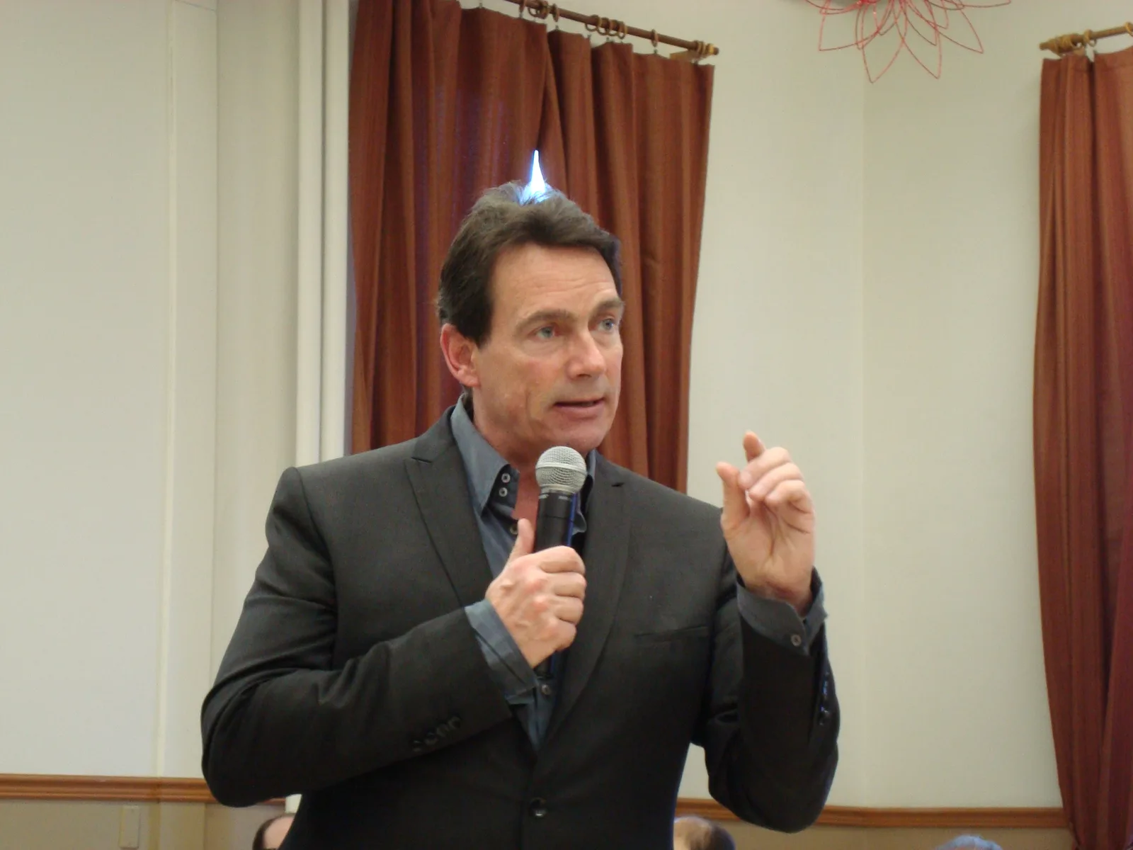 Pierre Karl Péladeau holds a microphone and gestures in front of red curtains while addressing Parti Québécois activists in December 2014; Samounet’s complete supplied frame.