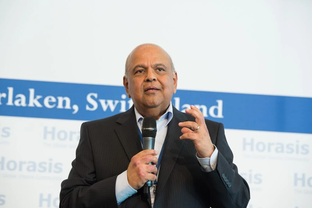 Pravin Gordhan holding a microphone before a Horasis meeting backdrop in 2015.
