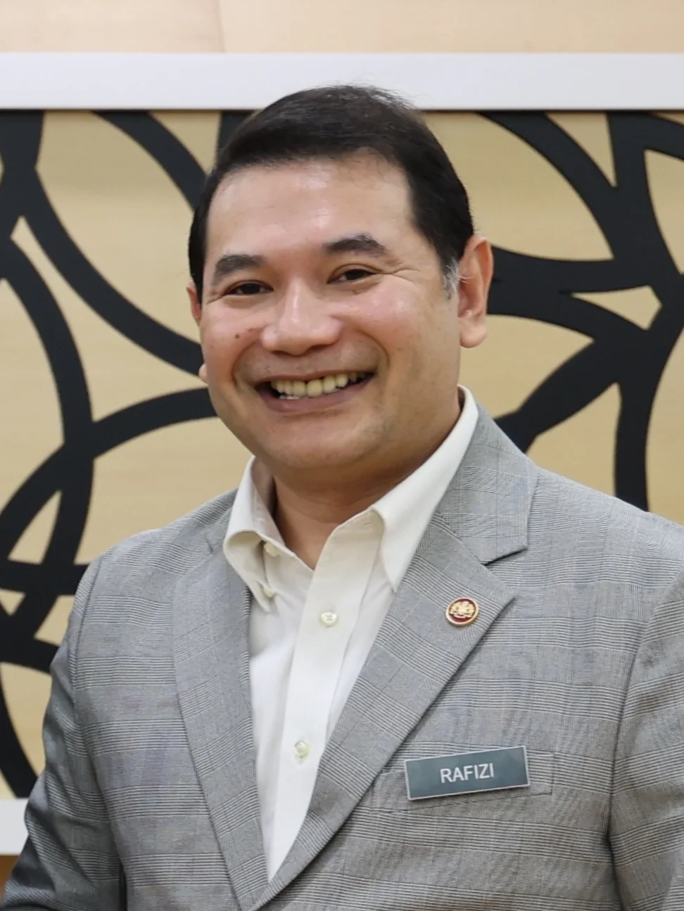 Rafizi Ramli wearing a grey suit and name badge during a US Embassy meeting in August 2023.