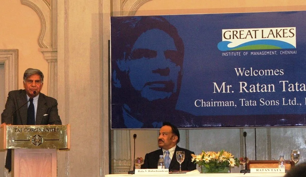 Ratan Naval Tata at the lectern on the left at a Great Lakes Institute of Management event in 2006, with a seated participant and the complete event banner.