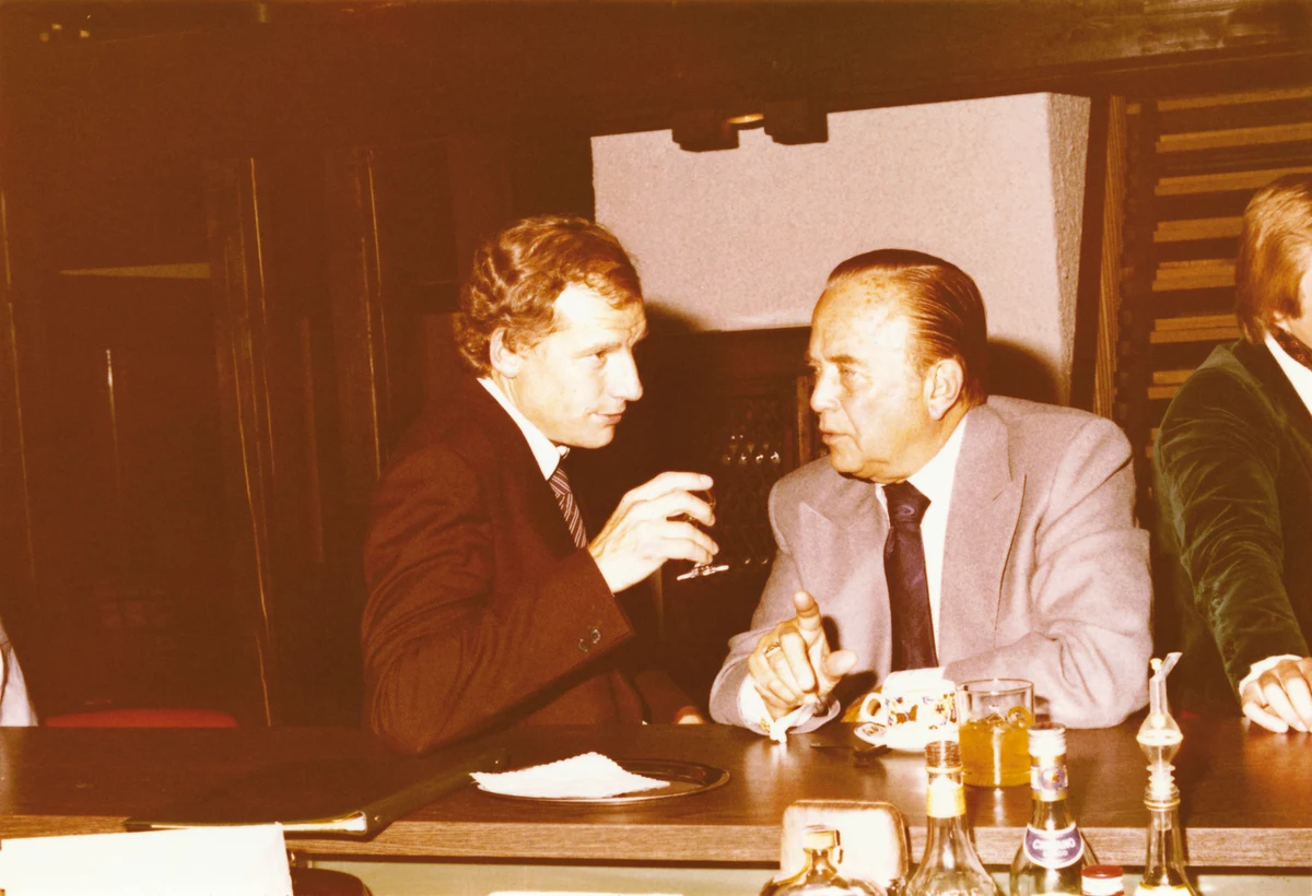 Ray Kroc seated at right with Jürgen Knauss at left in an undated historical photograph, with the full table, room and partial third person retained