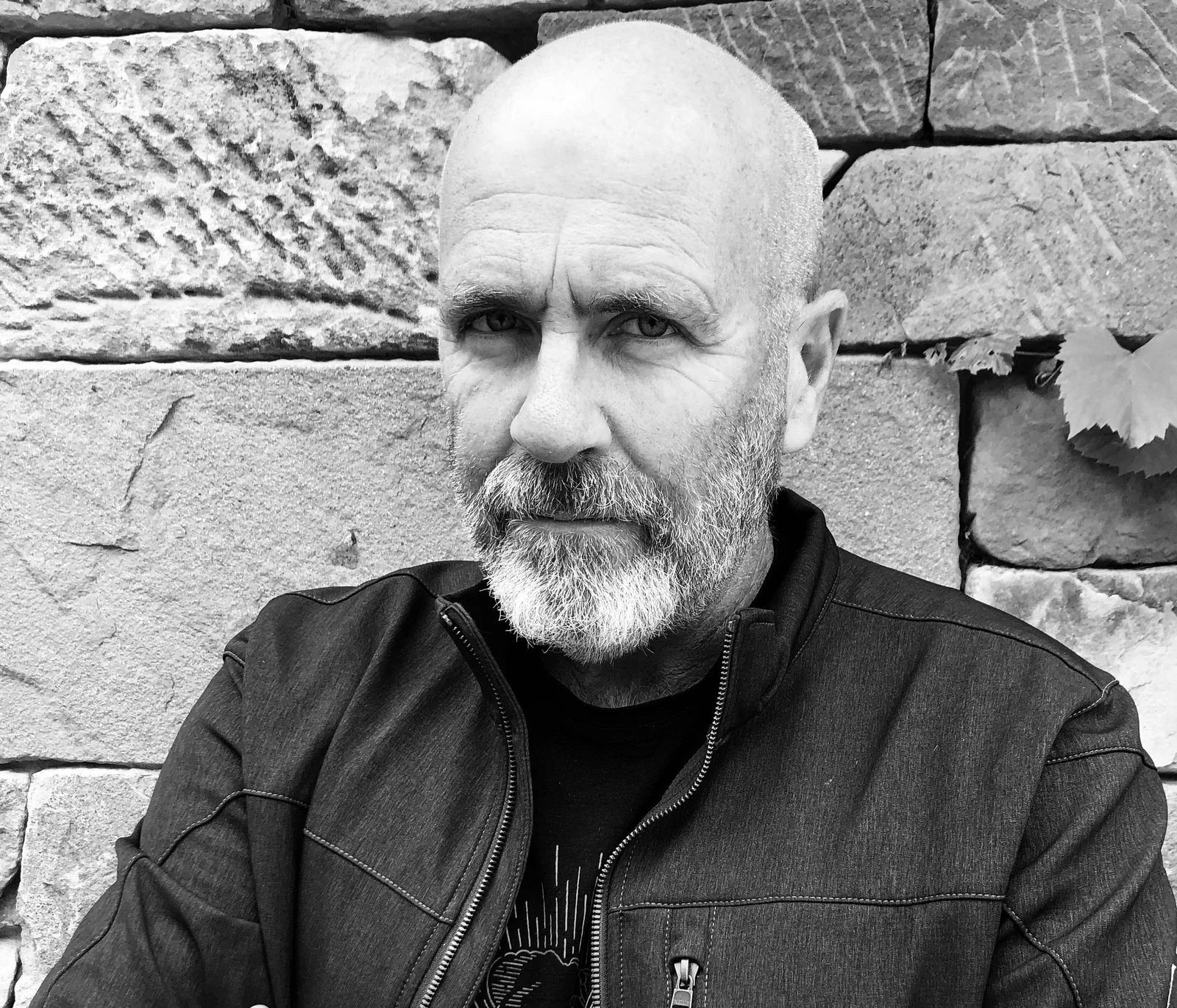 Richard Flanagan with a grey beard and dark jacket against a stone wall in the complete black-and-white photograph supplied in January 2021.