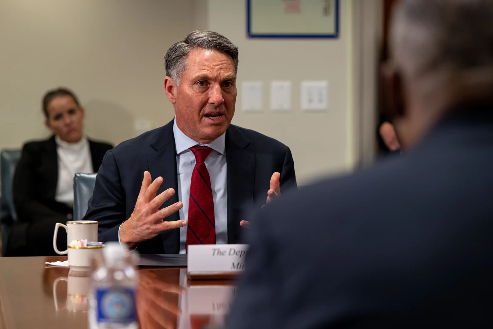 Richard Marles facing the camera during a 2023 Pentagon exchange, retaining the other attendee and Lloyd Austin’s foreground silhouette in the complete frame.