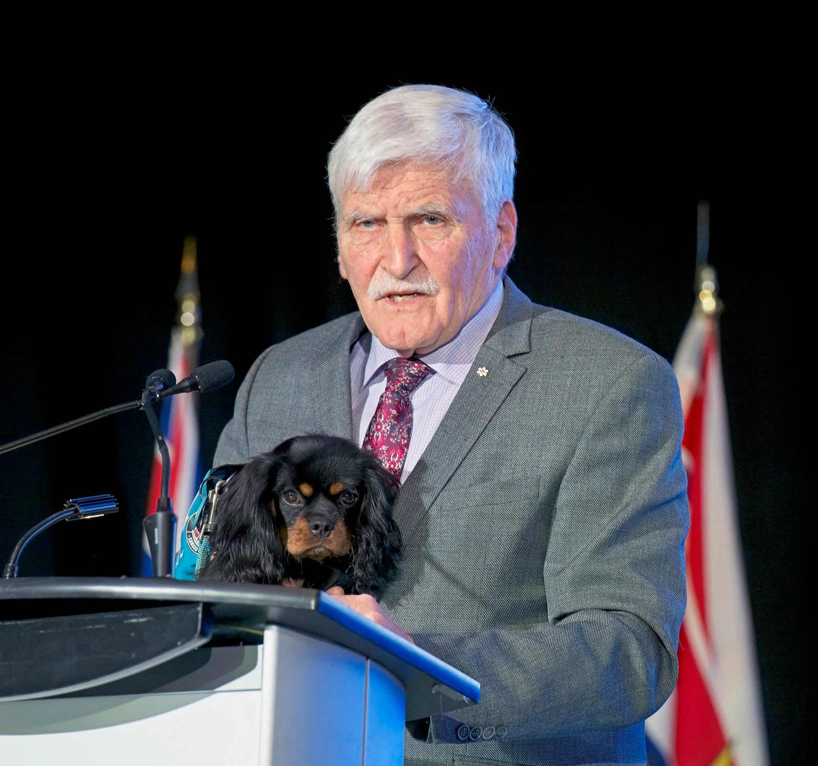 Roméo Dallaire speaking at a lectern while holding a small dog at the Ukrainian Canadian Congress in November 2025