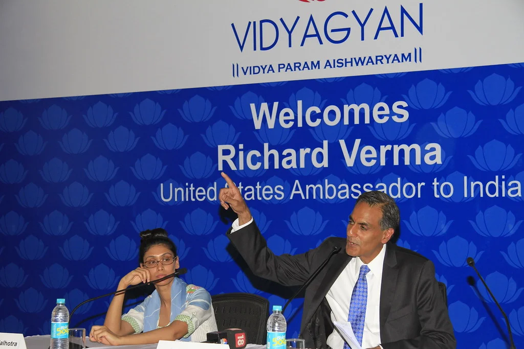 Roshni Nadar Malhotra seated at the left beside US Ambassador Richard Verma at a VidyaGyan event in May 2015; complete group frame, backdrop and nameplate retained.