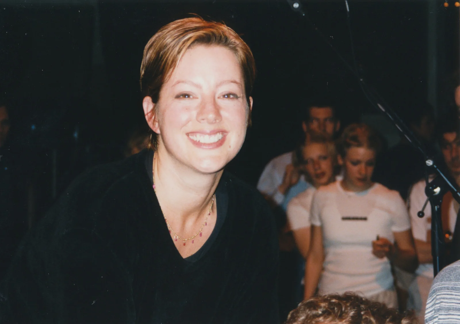 Sarah McLachlan smiling at Paradiso in Amsterdam in May 1999, with bystanders and a microphone stand behind her