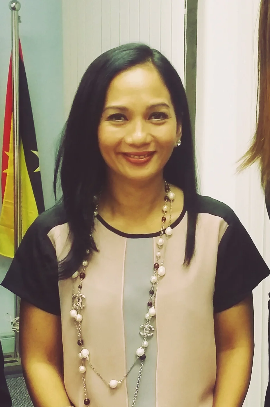 Sheila Majid wearing a black-and-cream outfit and a long necklace in a standing portrait.