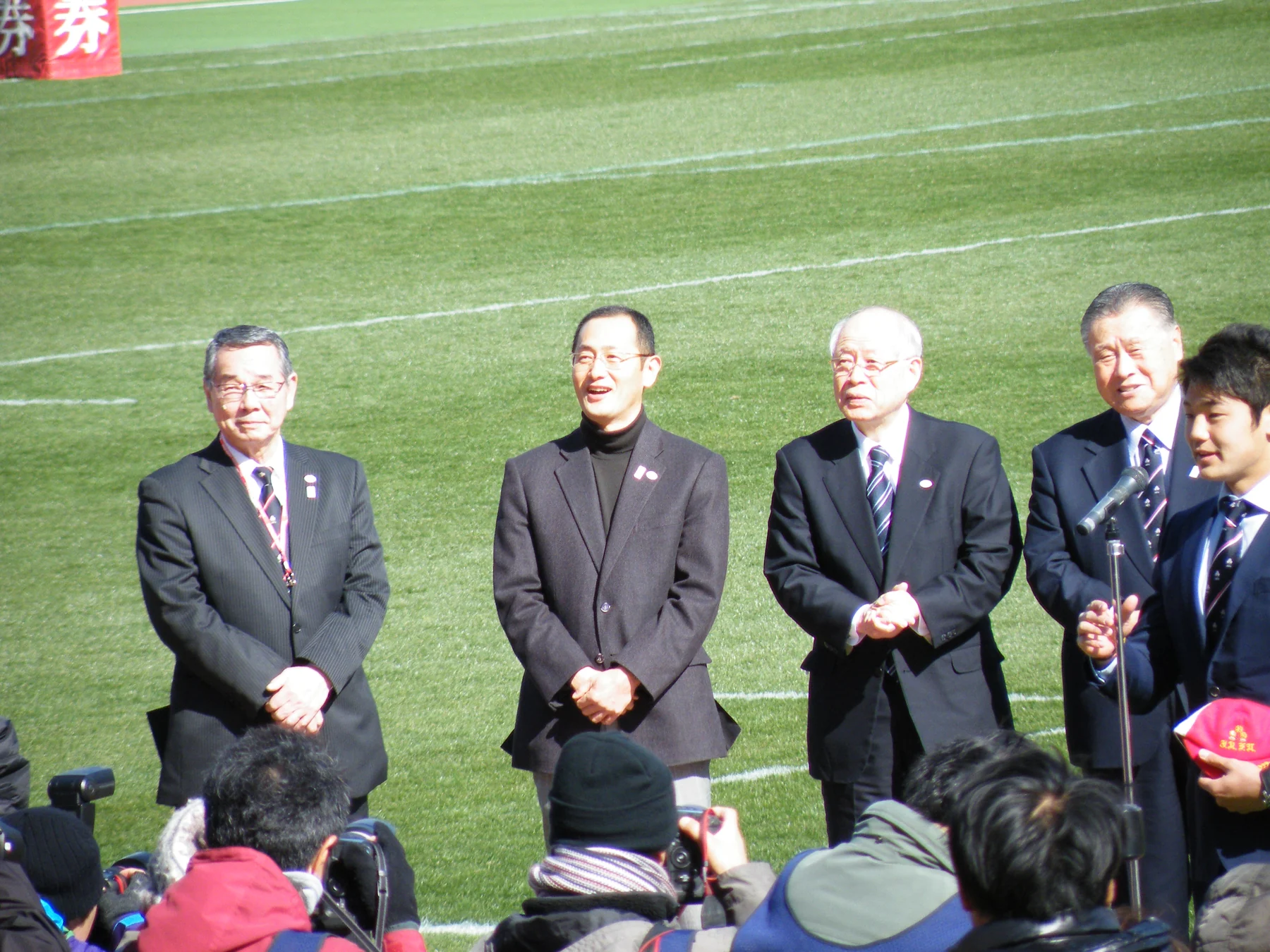 Shinya Yamanaka, second from left, with Tatsuzō Yabe, Ryōji Noyori, Yoshirō Mori and Yoshikazu Fujita before a rugby final, with photographers in the foreground.