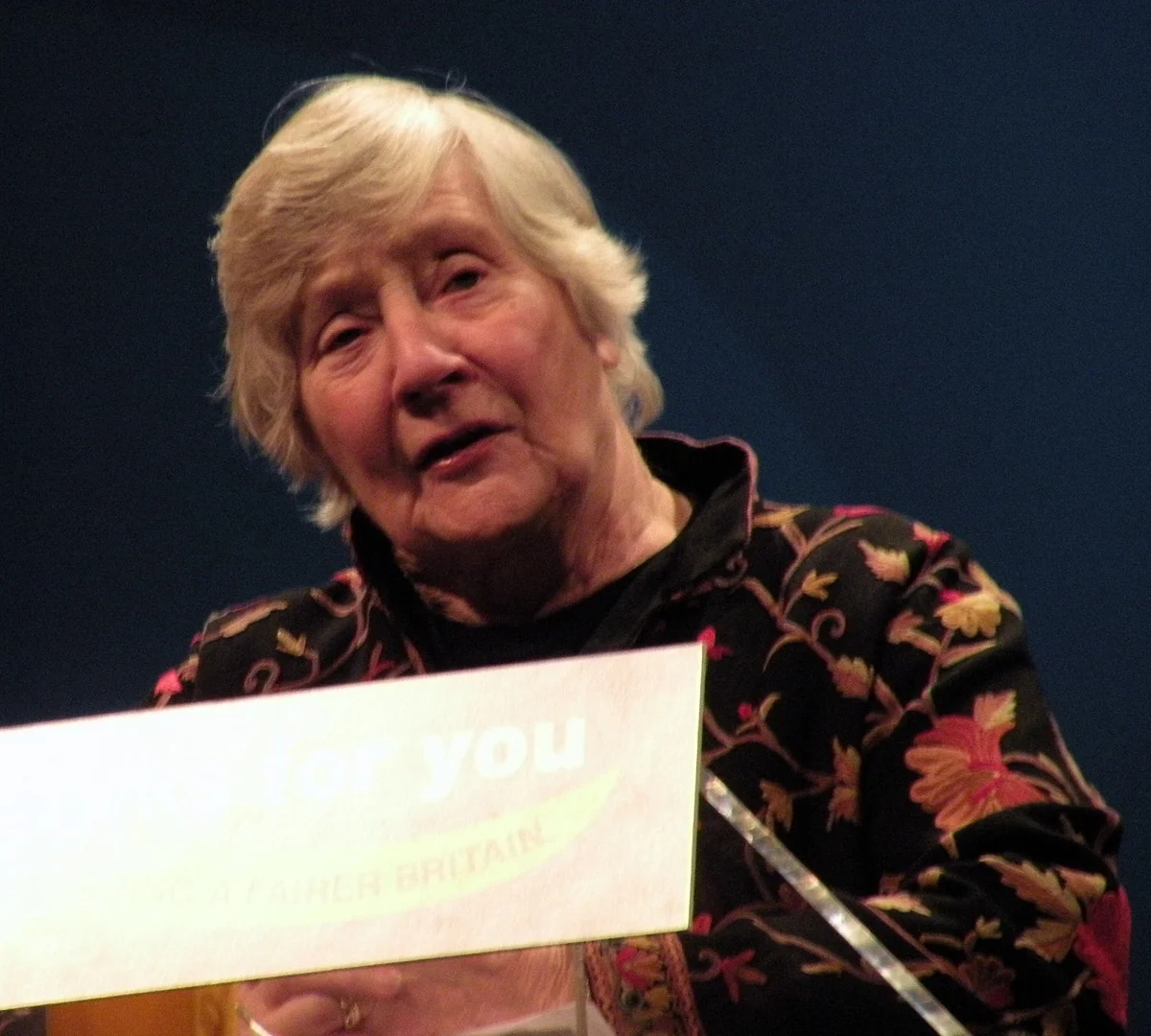 Shirley Williams speaking behind a lectern at a Liberal Democrat rally in Birmingham on 12 March 2010; complete frame retained.