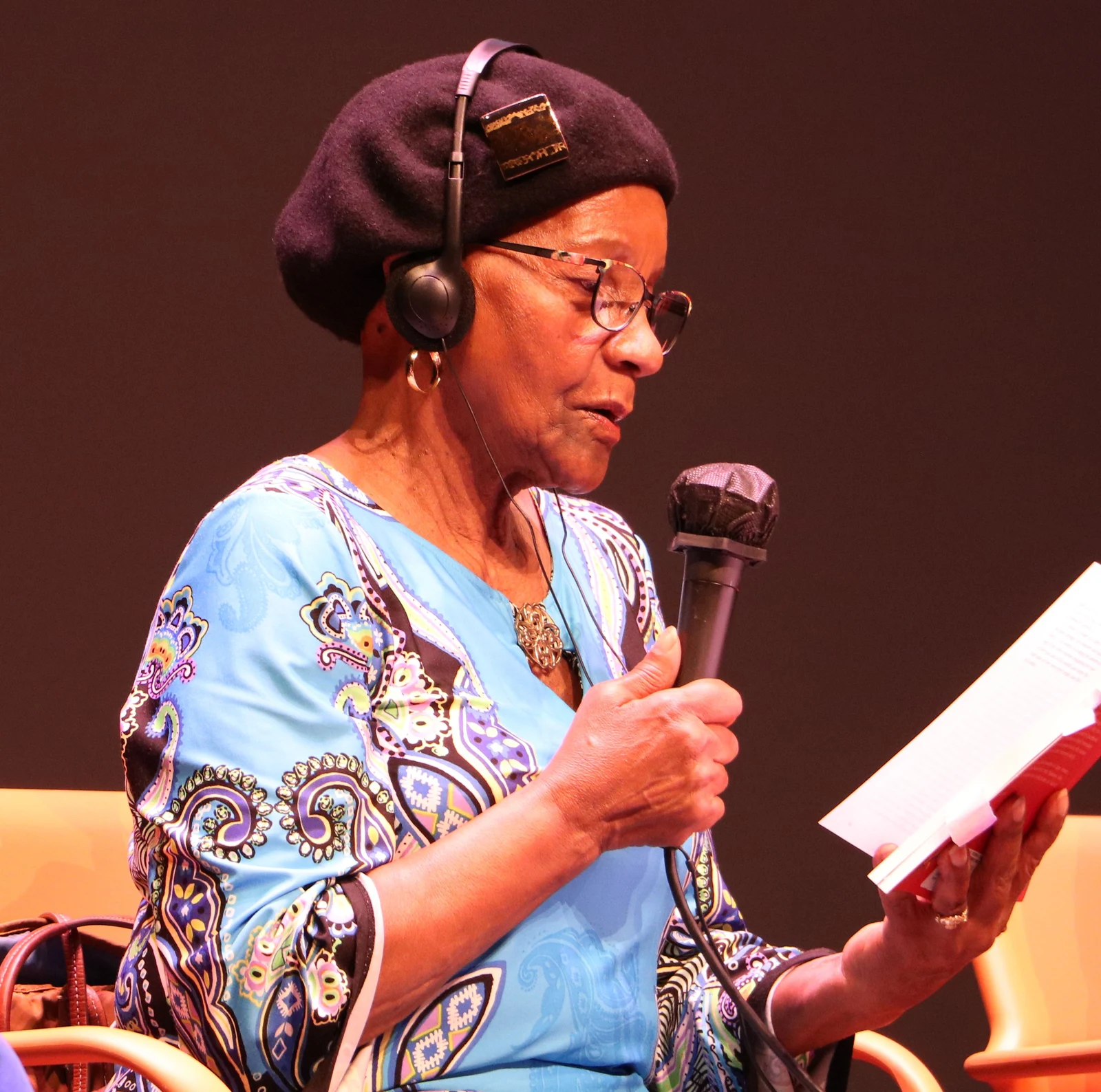 Sindiwe Magona holding a microphone and reading at Festival Atlantide in Nantes on 19 June 2021.