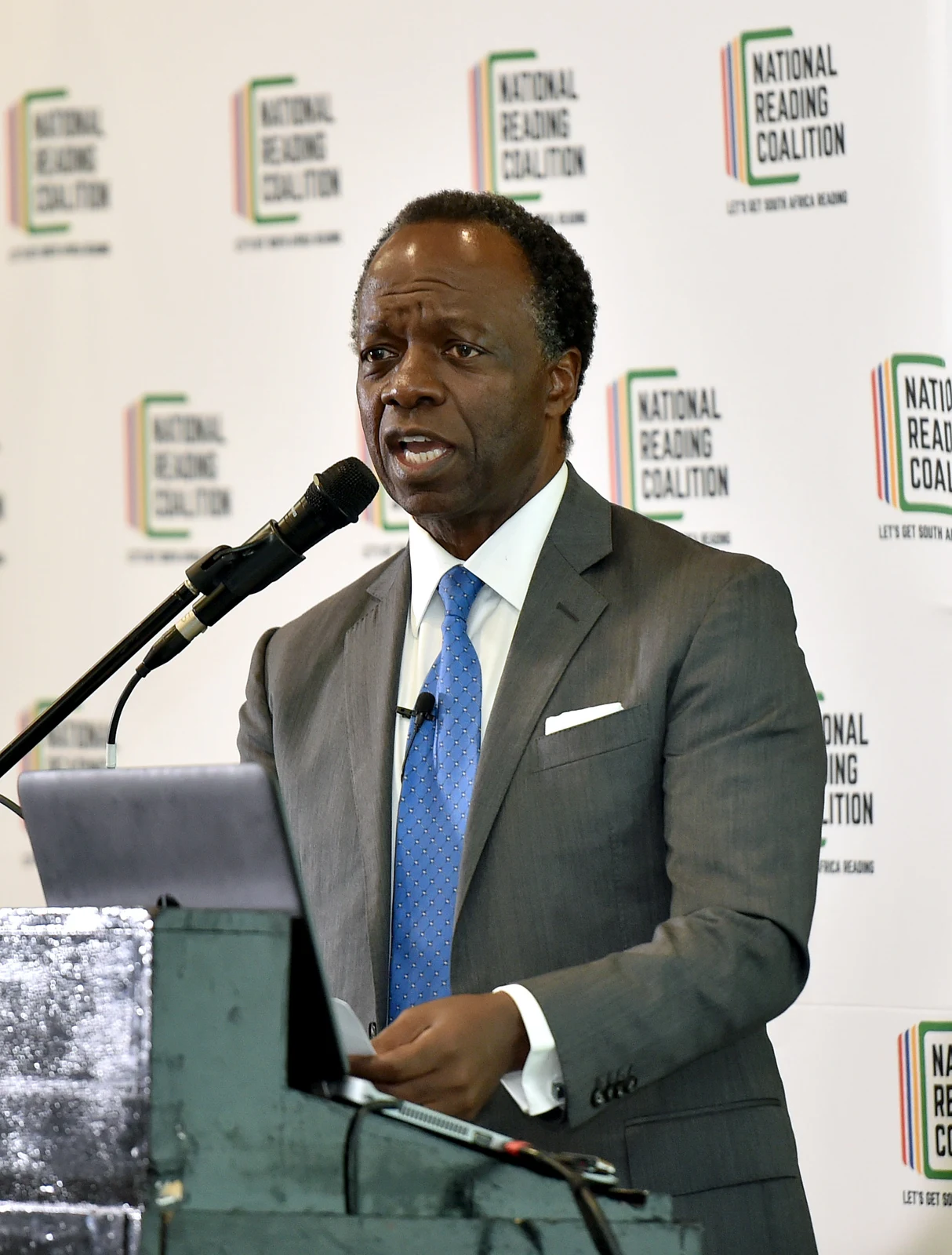 Sizwe Nxasana speaking at the 2019 National Reading Coalition launch, with the full lectern and event backdrop retained.